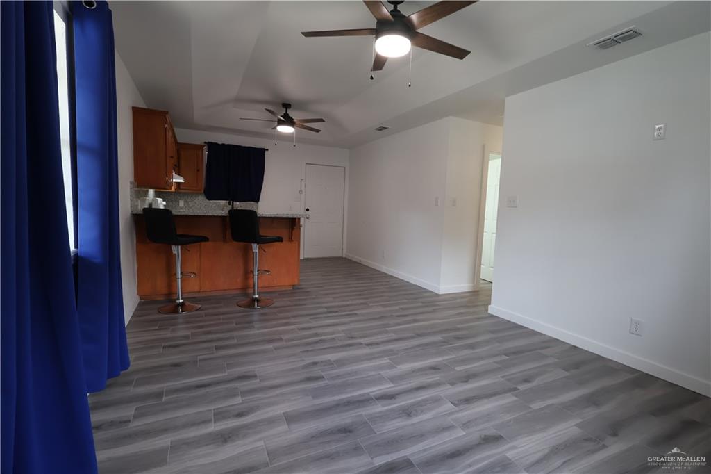 3526 Paseo Del Rey Edinburg, TX 78542 - Photo 3 of 20 Kitchen with wood finish cabinetry, a breakfast bar, ceiling fan, a peninsula, and tasteful backsplash