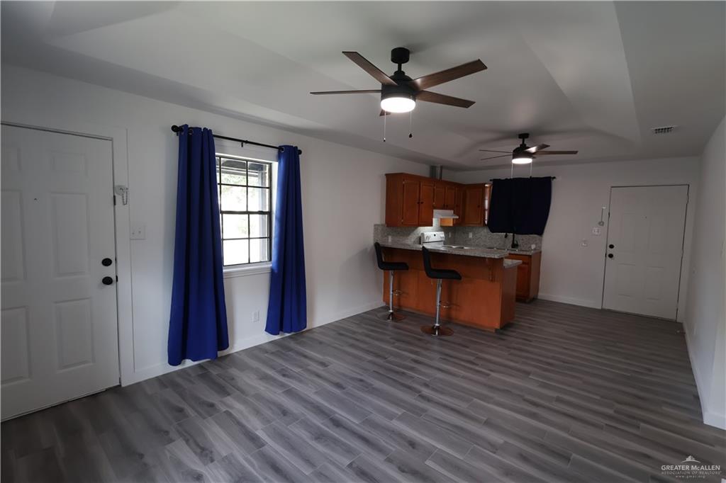 3526 Paseo Del Rey Edinburg, TX 78542 - Photo 4 of 20 Kitchen featuring wood finish cabinets, a kitchen bar, a peninsula, decorative backsplash, and ceiling fan