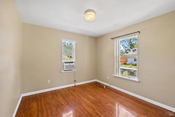 a view of an empty room with window and wooden floor