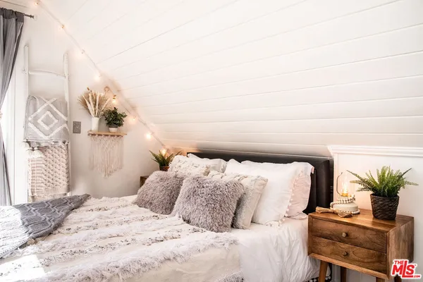 a bedroom with a bed and a lamp with the potted plant