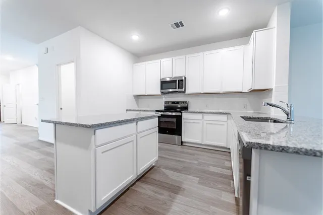 a kitchen with granite countertop white cabinets and white appliances