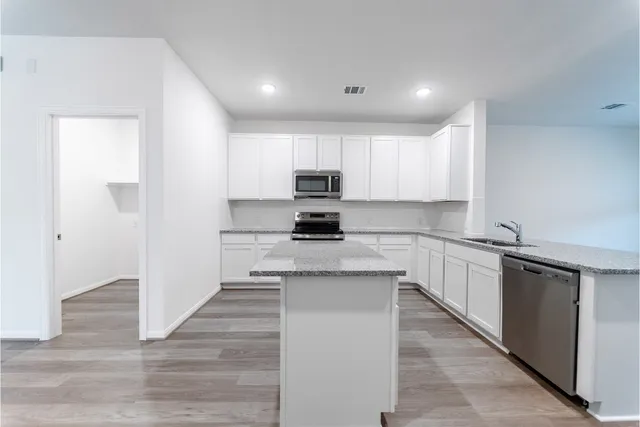 a kitchen with granite countertop white cabinets and black stainless steel appliances