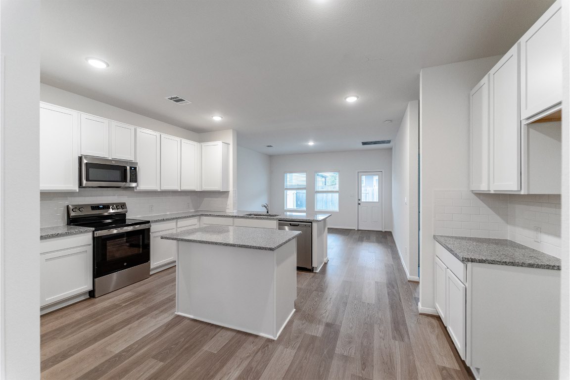 732 Barbary Coast Lane Jarrell, TX 76537 - Photo 4 of 17 a kitchen with stainless steel appliances kitchen island granite countertop a stove top oven a sink a counter space and cabinets