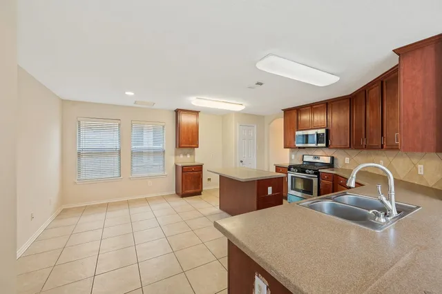 a kitchen with sink a refrigerator and wooden cabinets