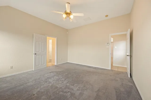 an empty room with chandelier fan and windows