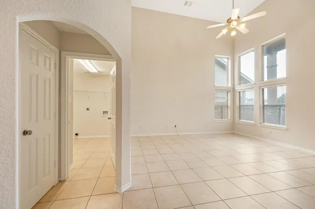 a view of an empty room with window and chandelier fan