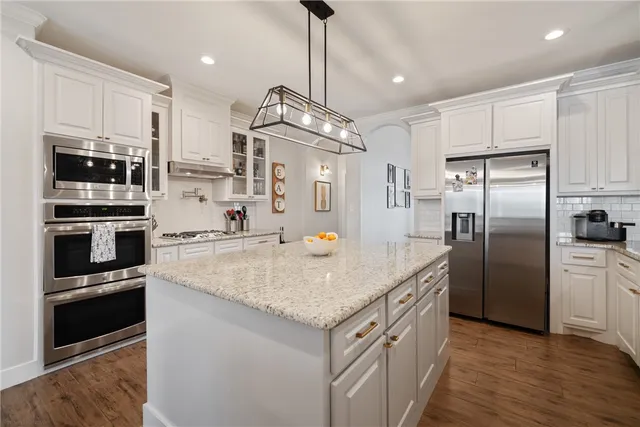a kitchen with stainless steel appliances granite countertop a sink a stove and a refrigerator