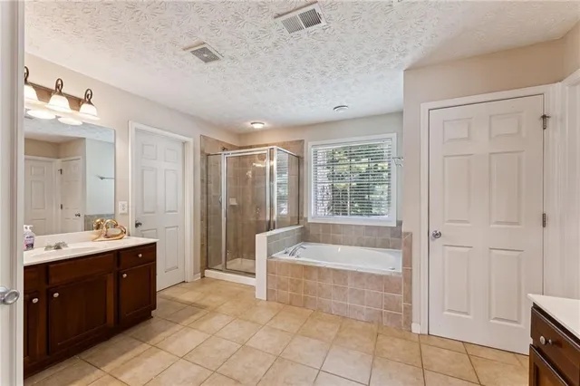 a spacious bathroom with a tub sink shower and mirror