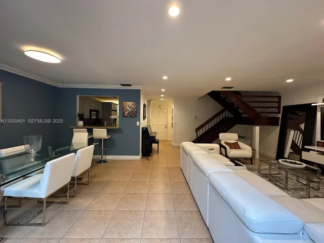 a living room with furniture a table and kitchen view