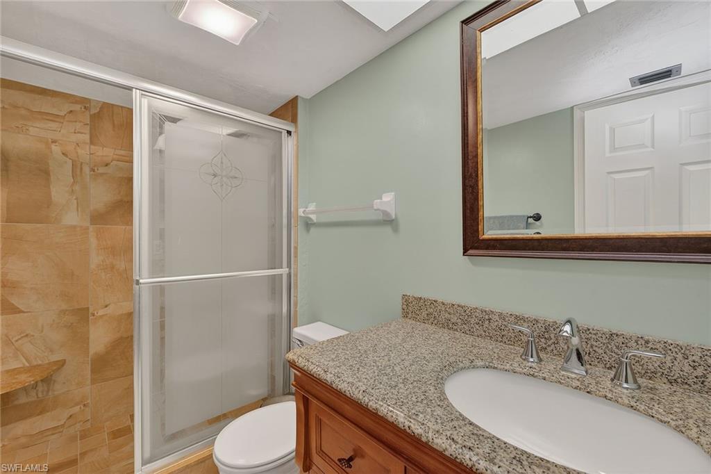 1400 Blue Point Avenue, Unit 202 Naples, FL 34102 - Photo 12 of 18 a bathroom with a granite countertop sink toilet a mirror and shower