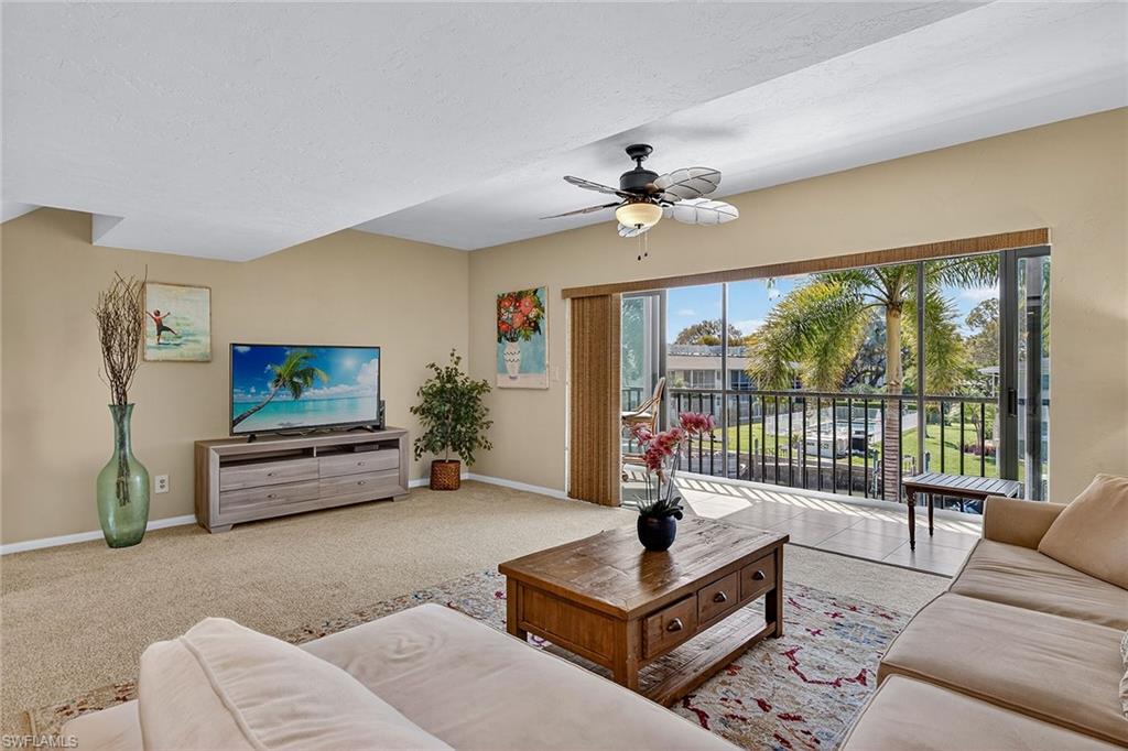 1400 Blue Point Avenue, Unit 202 Naples, FL 34102 - Photo 3 of 18 a living room with furniture a flat screen tv and a large window