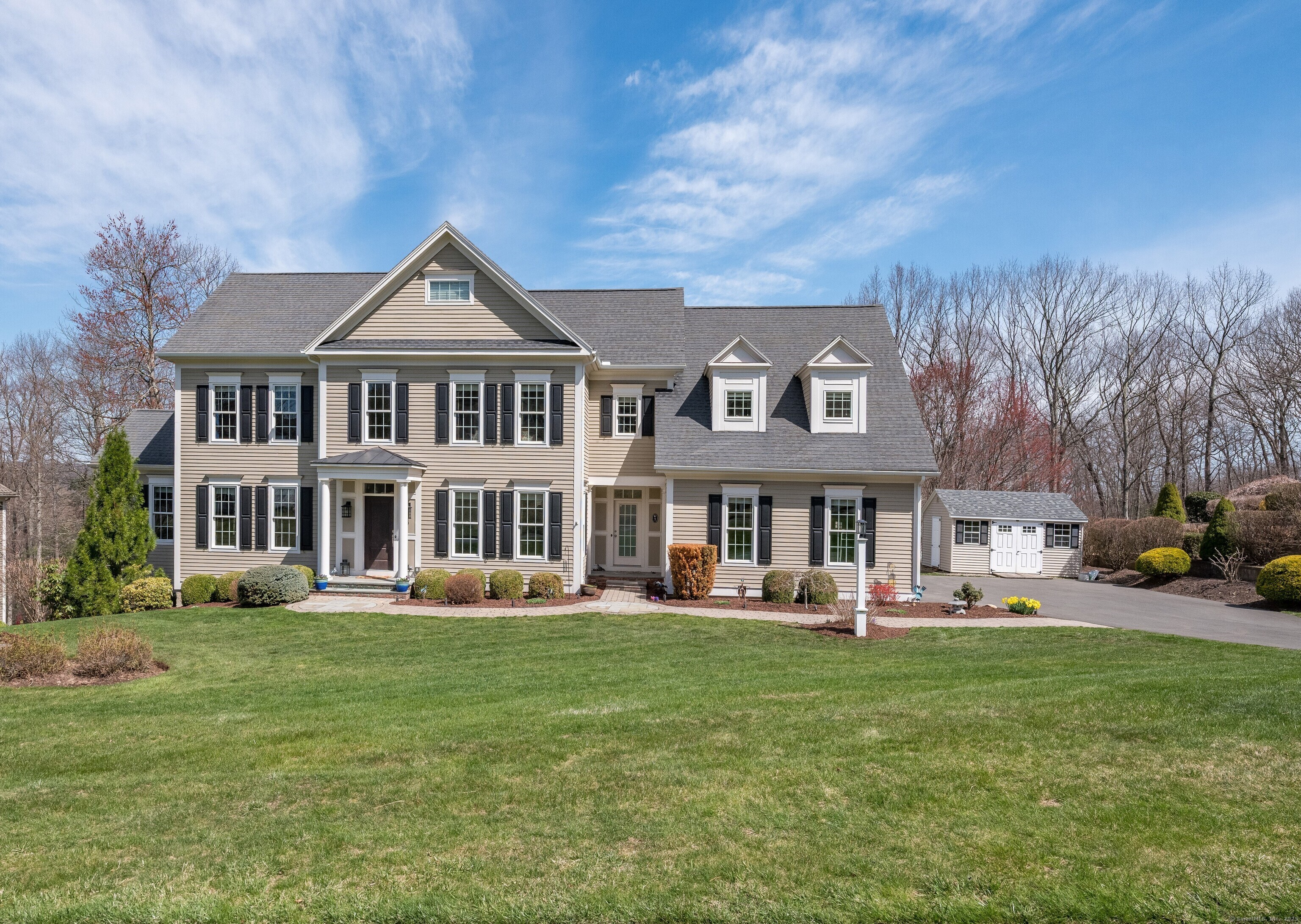 a front view of a house with garden and trees
