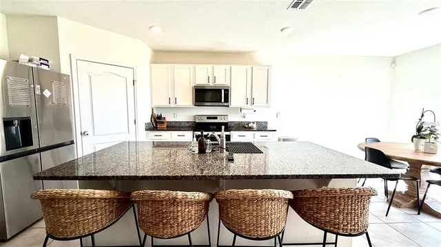 a kitchen with granite countertop a stove a sink a dining table and chairs
