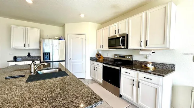 a kitchen with granite countertop a sink stove and refrigerator