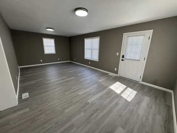 an empty room with wooden floor and windows