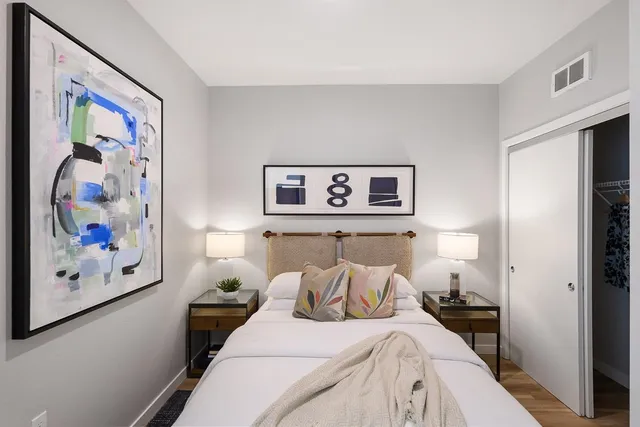 a bedroom with a bed and a lamp on dresser