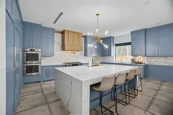 a kitchen with kitchen island granite countertop a sink counter and chairs