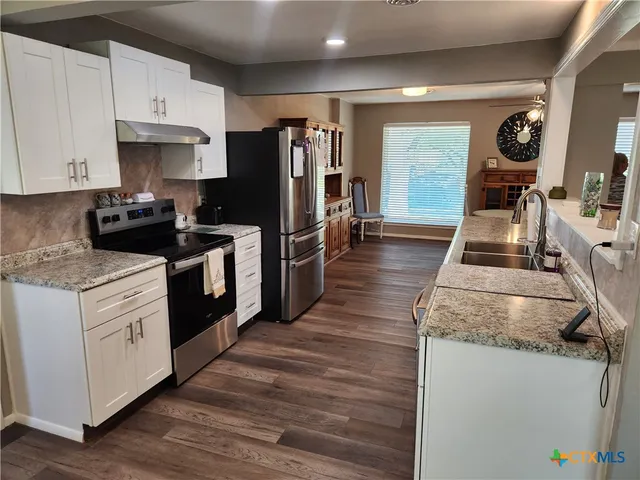 a kitchen with granite countertop a refrigerator stove and sink