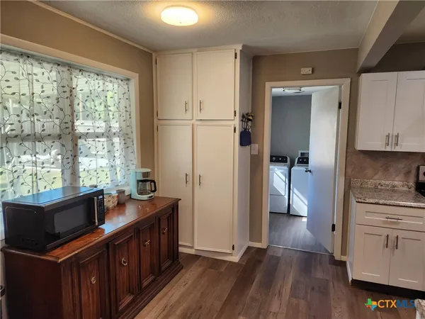 a kitchen with stainless steel appliances granite countertop a refrigerator a sink dishwasher a stove and white countertops with wooden floor