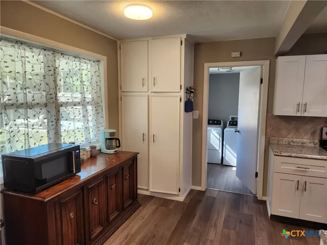 a kitchen with stainless steel appliances granite countertop a refrigerator a sink dishwasher a stove and white countertops with wooden floor