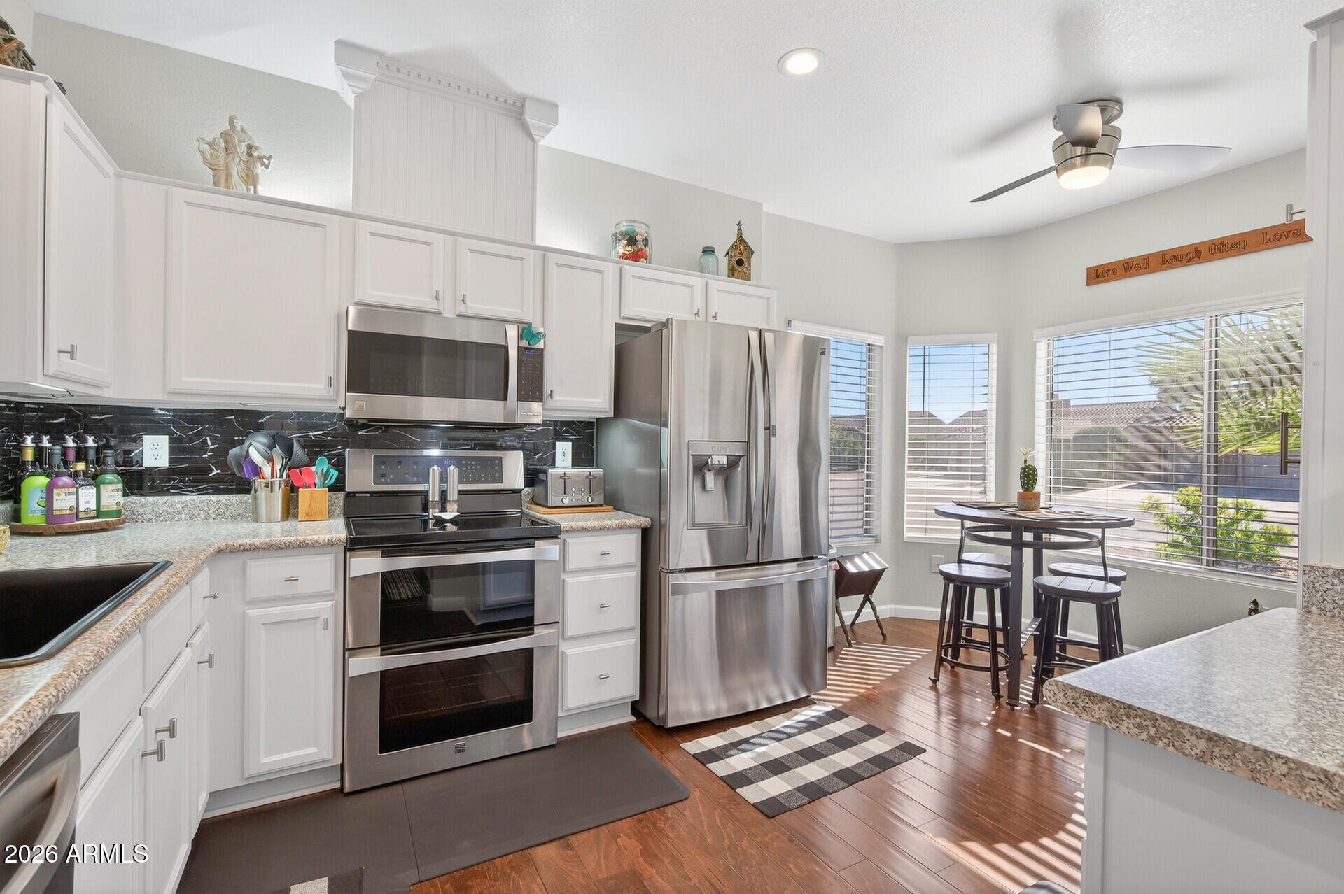 16100 West Eagle Ridge Drive Surprise, AZ 85374 - Photo 1 of 44 a kitchen with stainless steel appliances a stove a sink dishwasher a refrigerator and a dining table with wooden floor