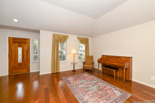a living room with a couch and piano table with wooden floor
