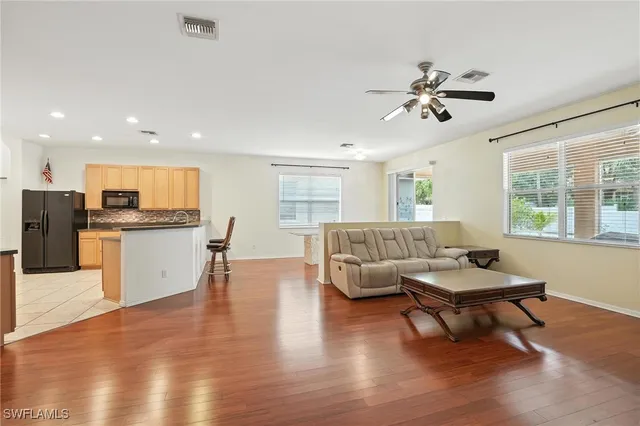 a living room with furniture and kitchen view with wooden floor