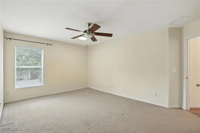 an empty room with a window and a fan