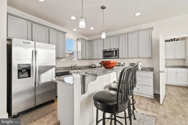 a kitchen with stainless steel appliances granite countertop a refrigerator a stove a sink a dining table and chairs with wooden floor