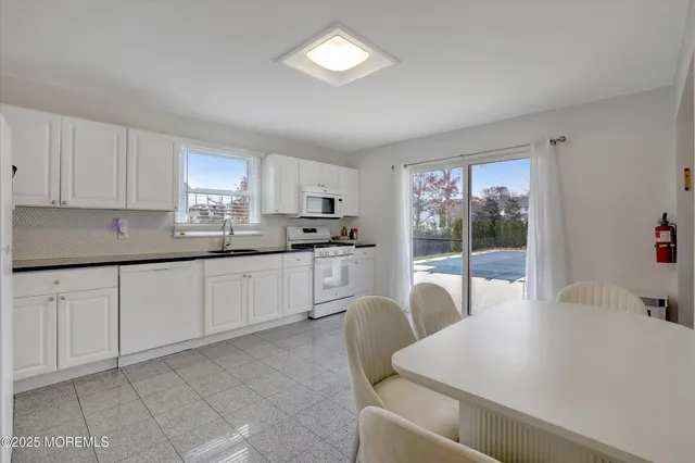 a kitchen with stainless steel appliances a white table chairs and a refrigerator
