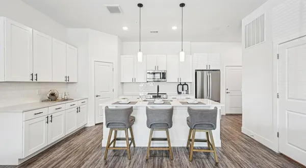 a kitchen with stainless steel appliances a white table chairs and a refrigerator