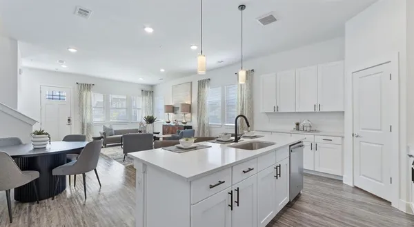 a kitchen with sink stove and white cabinets with wooden floor