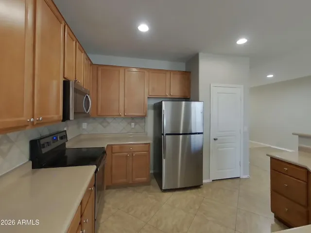 a kitchen with a refrigerator a stove top oven and cabinets