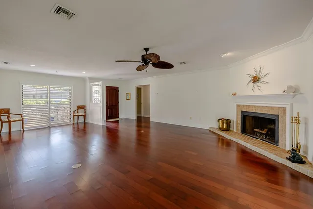 an empty room with wooden floor fireplace and windows