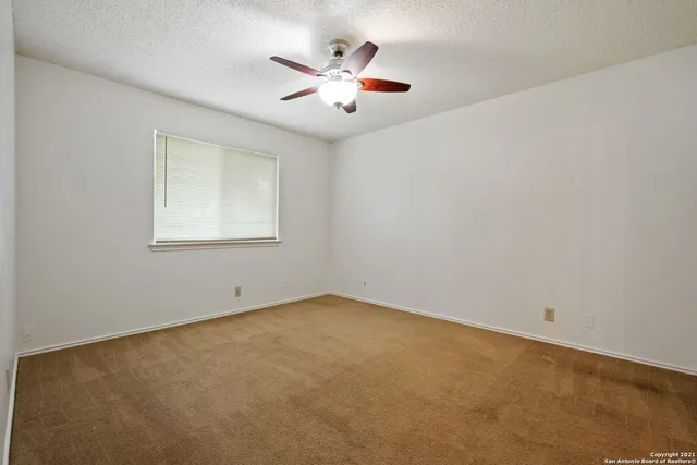 an empty room with ceiling fan and window