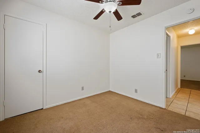 an empty room with a ceiling fan and carpet