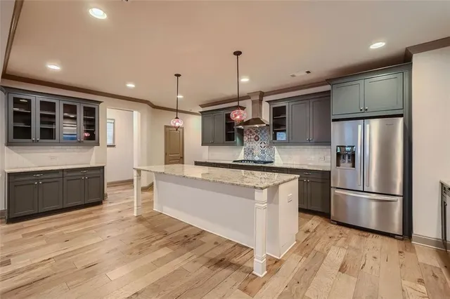 a large kitchen with stainless steel appliances kitchen island granite countertop a refrigerator and a stove top oven