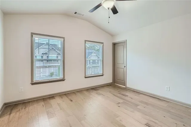 a view of an empty room with a window and wooden floor