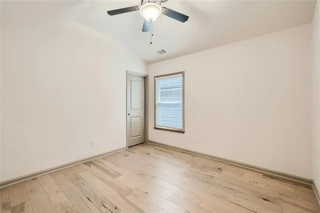 an empty room with a ceiling fan and window