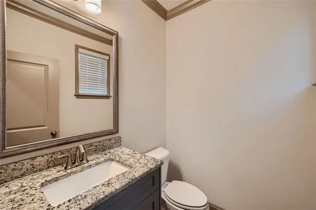 a bathroom with a granite countertop sink toilet and mirror