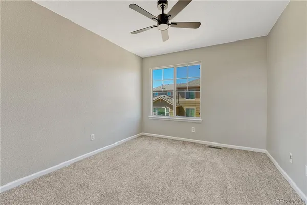 an empty room with window and ceiling fan