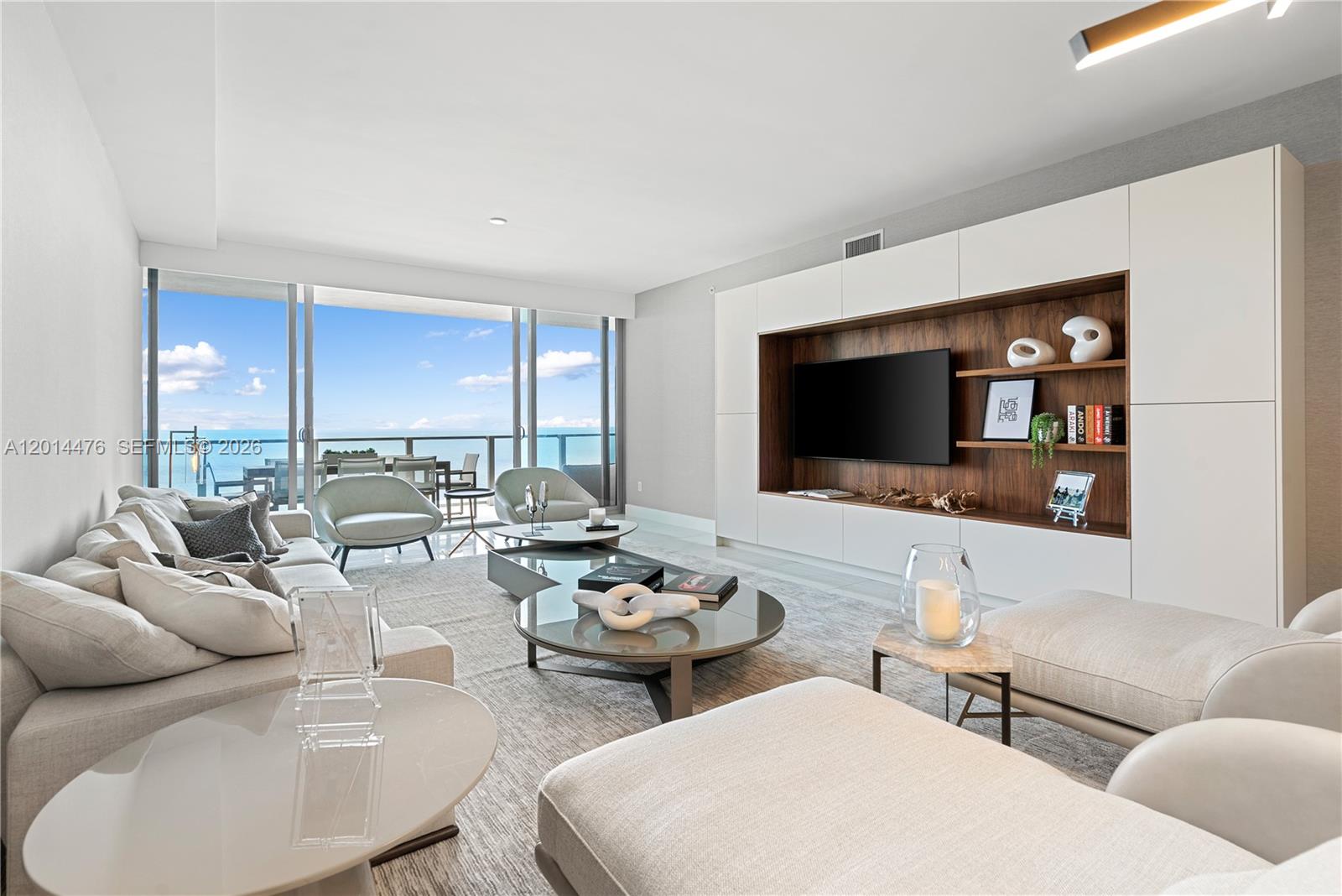 360 Ocean Drive, Unit 1106S Key Biscayne, FL 33149 - Photo 8 of 67 Living Room / Balcony View – This sunlit living space highlights the home’s indoor-outdoor connection, with sliding glass doors leading to a private balcony overlooking the water. A custom entertainment wall and neutral palette keep the space sleek and inviting.