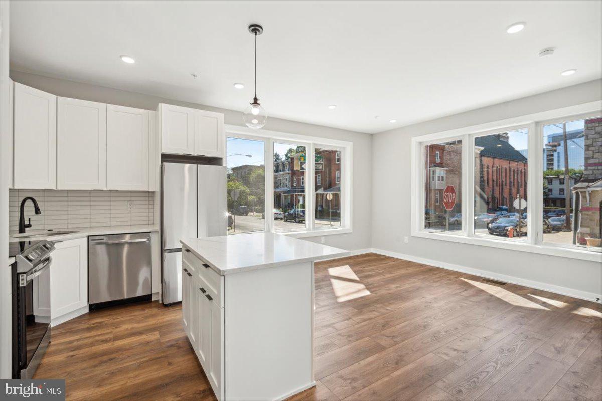 3801 Hamilton Street, Unit B Philadelphia, PA 19104 - Photo 6 of 46 a kitchen with stainless steel appliances granite countertop a stove a sink dishwasher a refrigerator and white cabinets with wooden floor