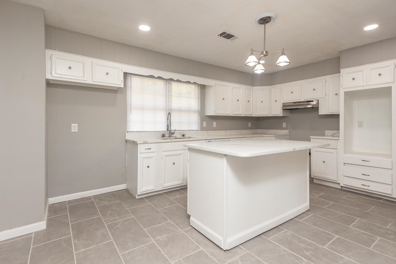 3864 Hobson Road Memphis, TN 38128 - Photo 5 of 19 Kitchen featuring sink, light stone countertops, white cabinetry, and decorative light fixtures