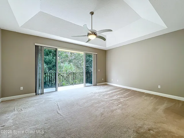 a view of an empty room with windows and ceiling fan
