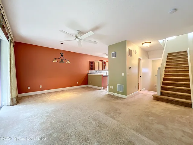 an empty room with wooden floor ceiling fan and windows