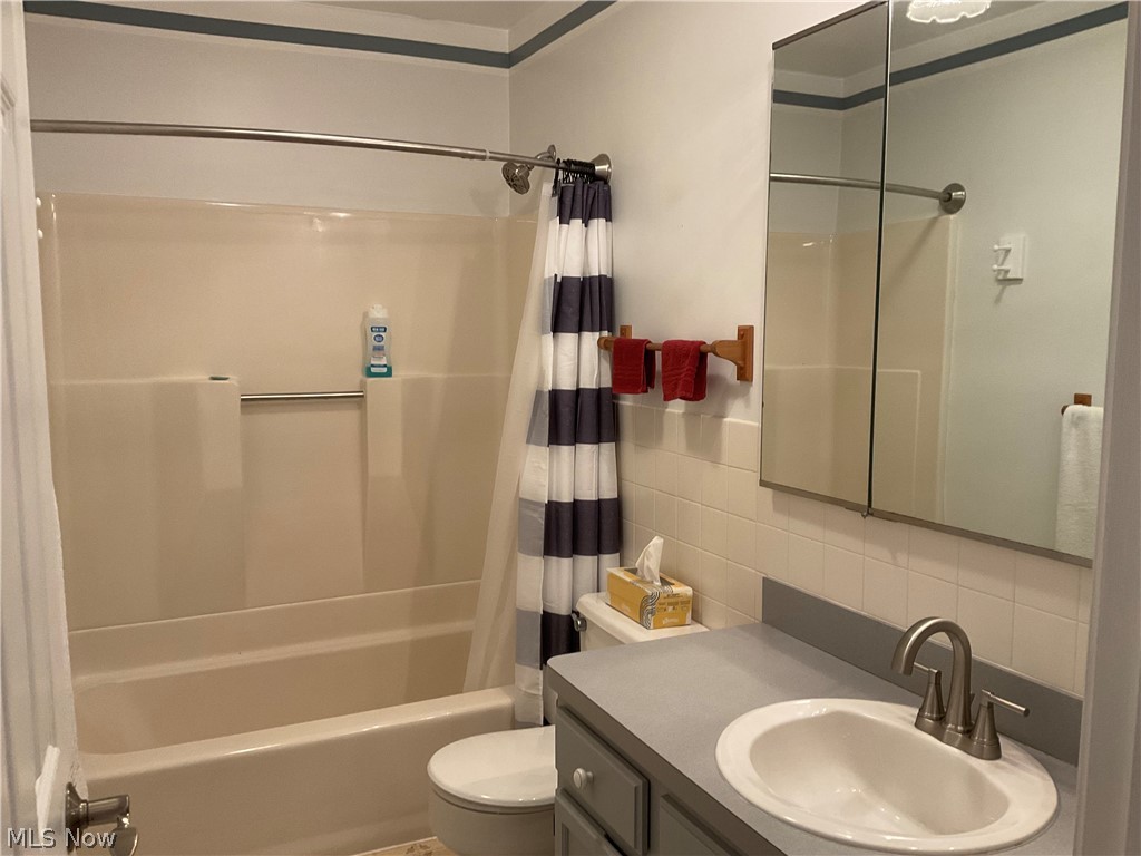 5360 Chapel Road Madison, OH 44057 - Photo 12 of 34 Full bathroom featuring tasteful backsplash, toilet, vanity, tile walls, and shower / bath combo