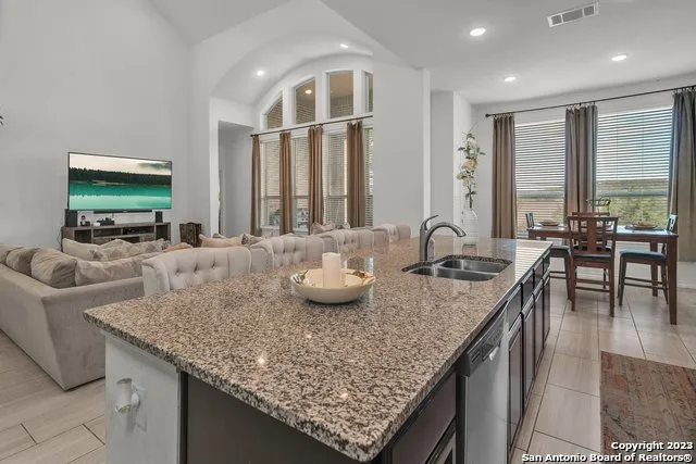 a kitchen with granite countertop kitchen island stainless steel appliances a sink and a living room