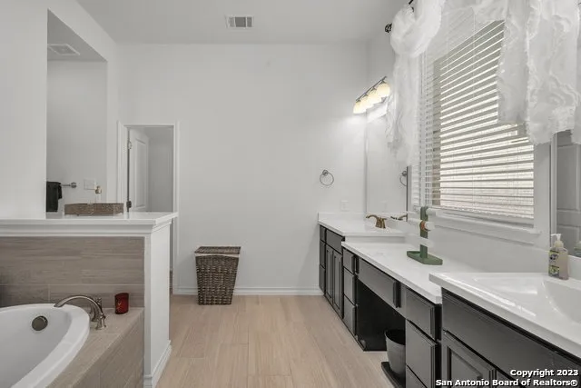 a spacious bathroom with a double vanity sink a mirror and a bathtub
