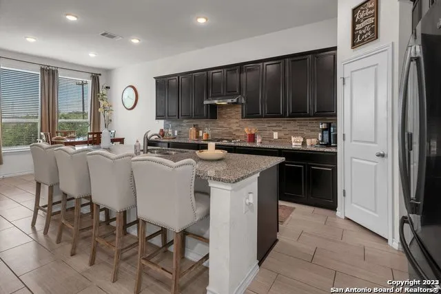 a kitchen with stainless steel appliances granite countertop a sink a stove a refrigerator and cabinets